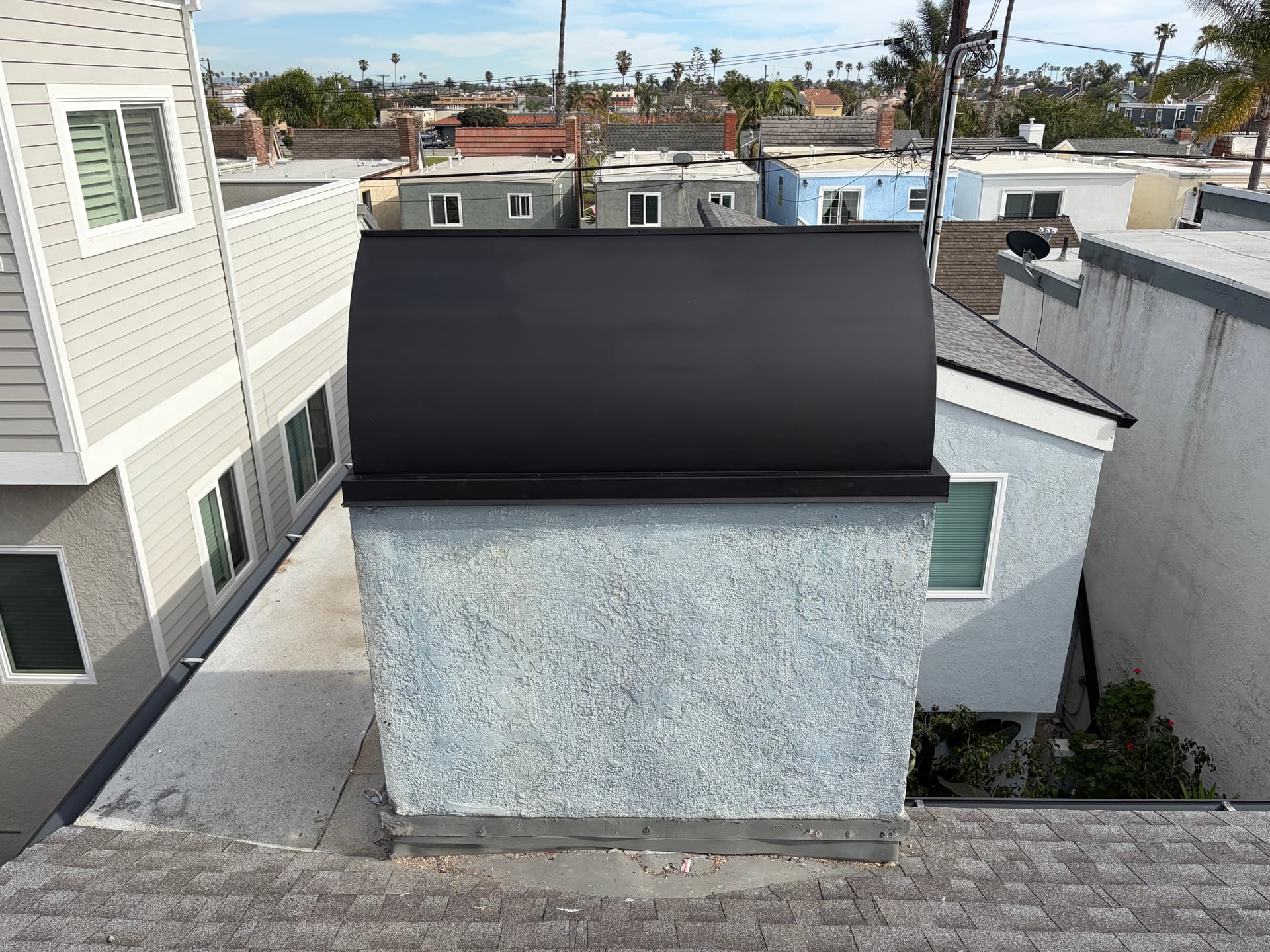Completed black chimney shroud installation viewed from above on a coastal home