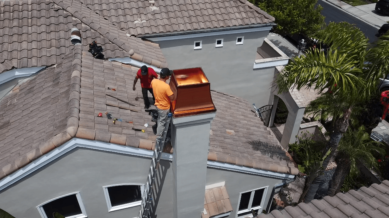 Rain Gutter Guys crew installing a copper chimney shroud on a tile roof