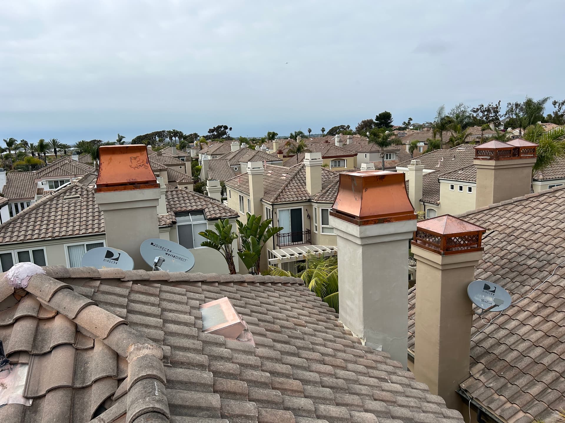 Multiple copper chimney caps installed across neighborhood rooftops in Southern California