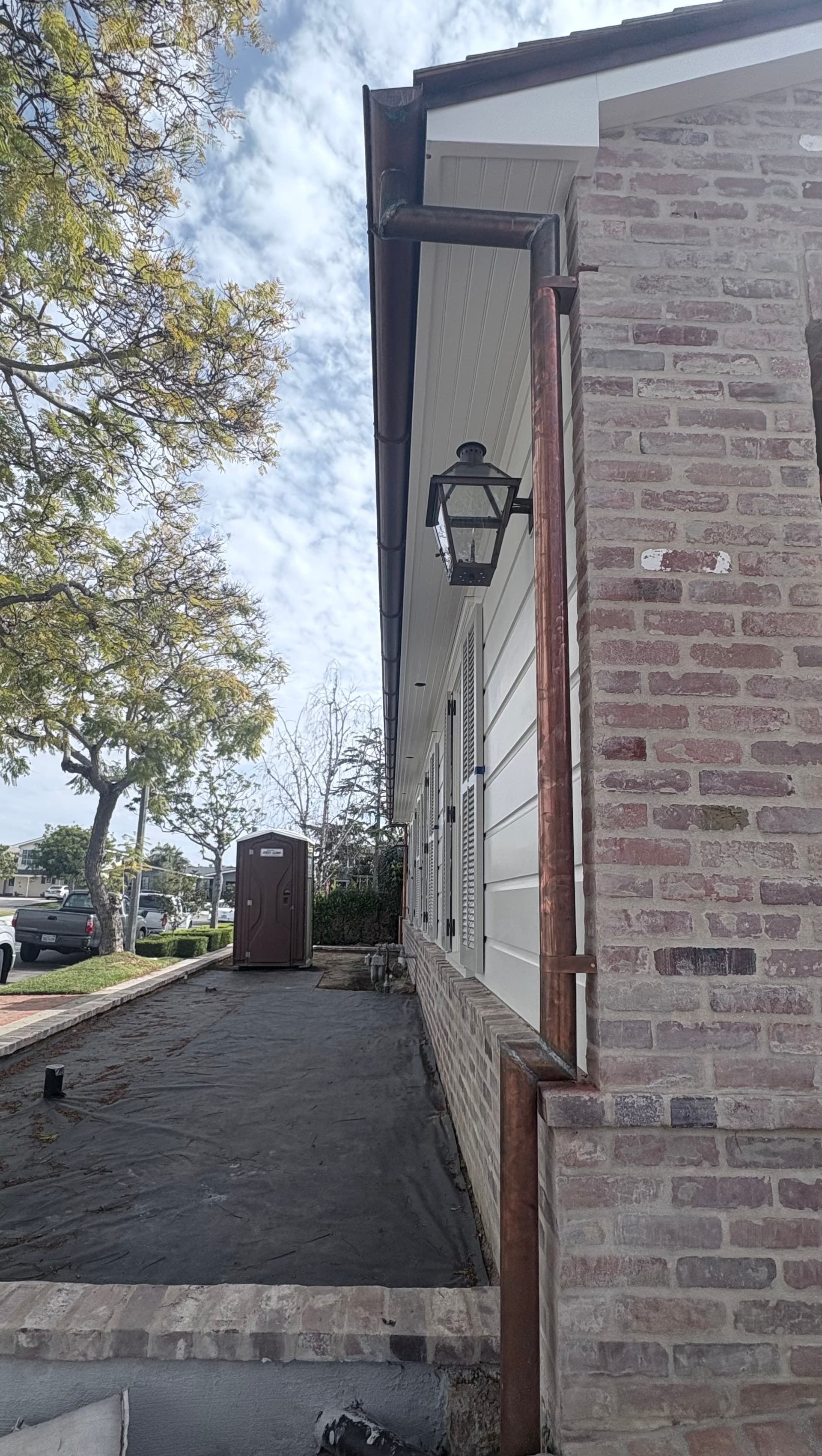 Copper round downspout on a brick home with lantern fixture