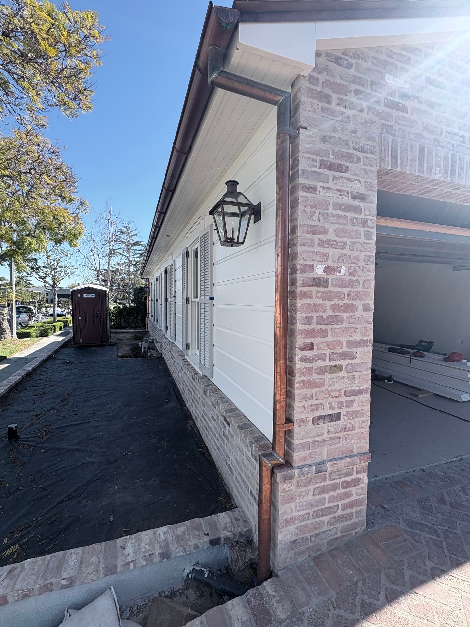 Copper half-round gutter and downspout on brick porch with lantern