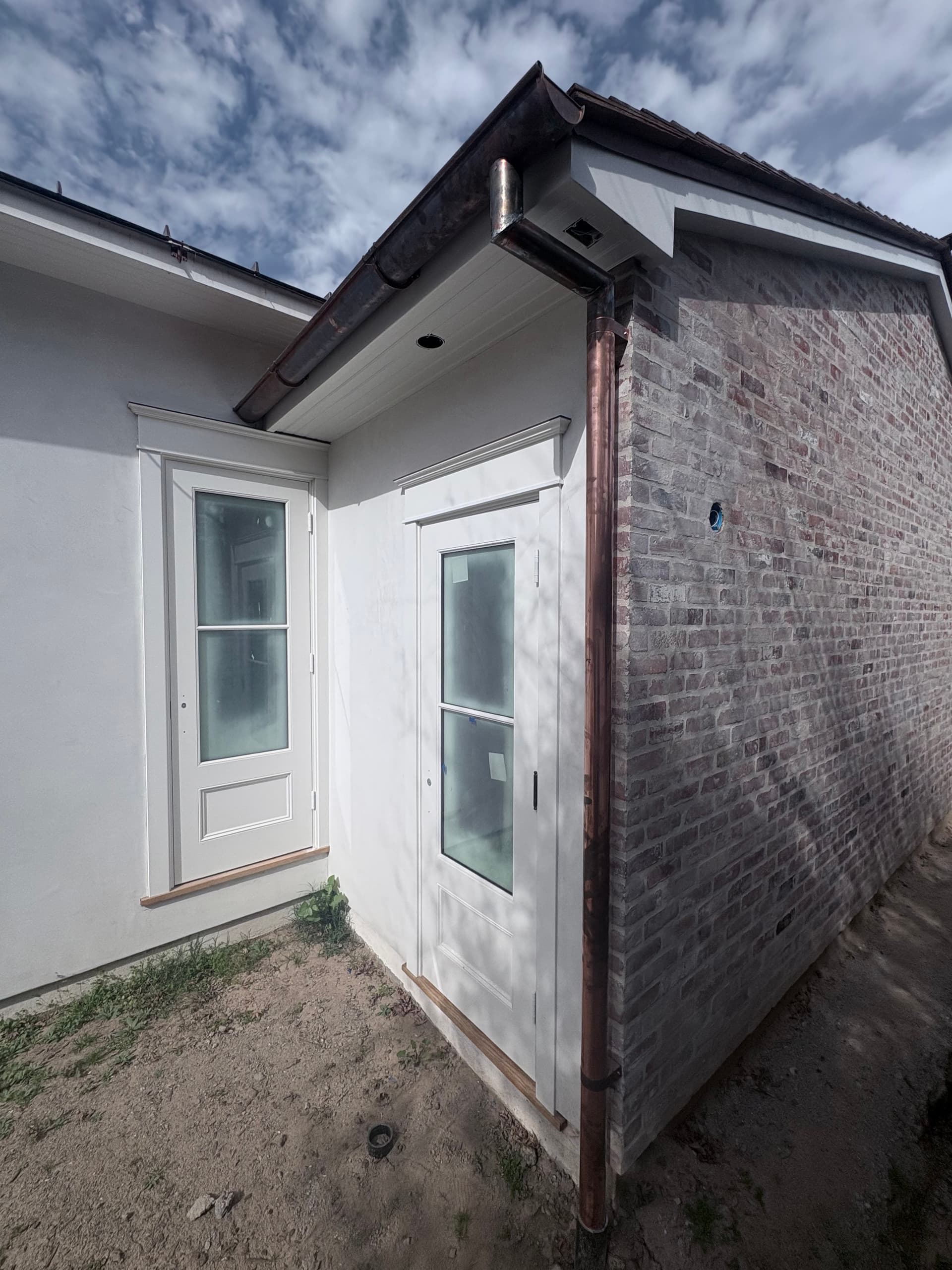 Copper half-round gutter on two-story home with brick and windows