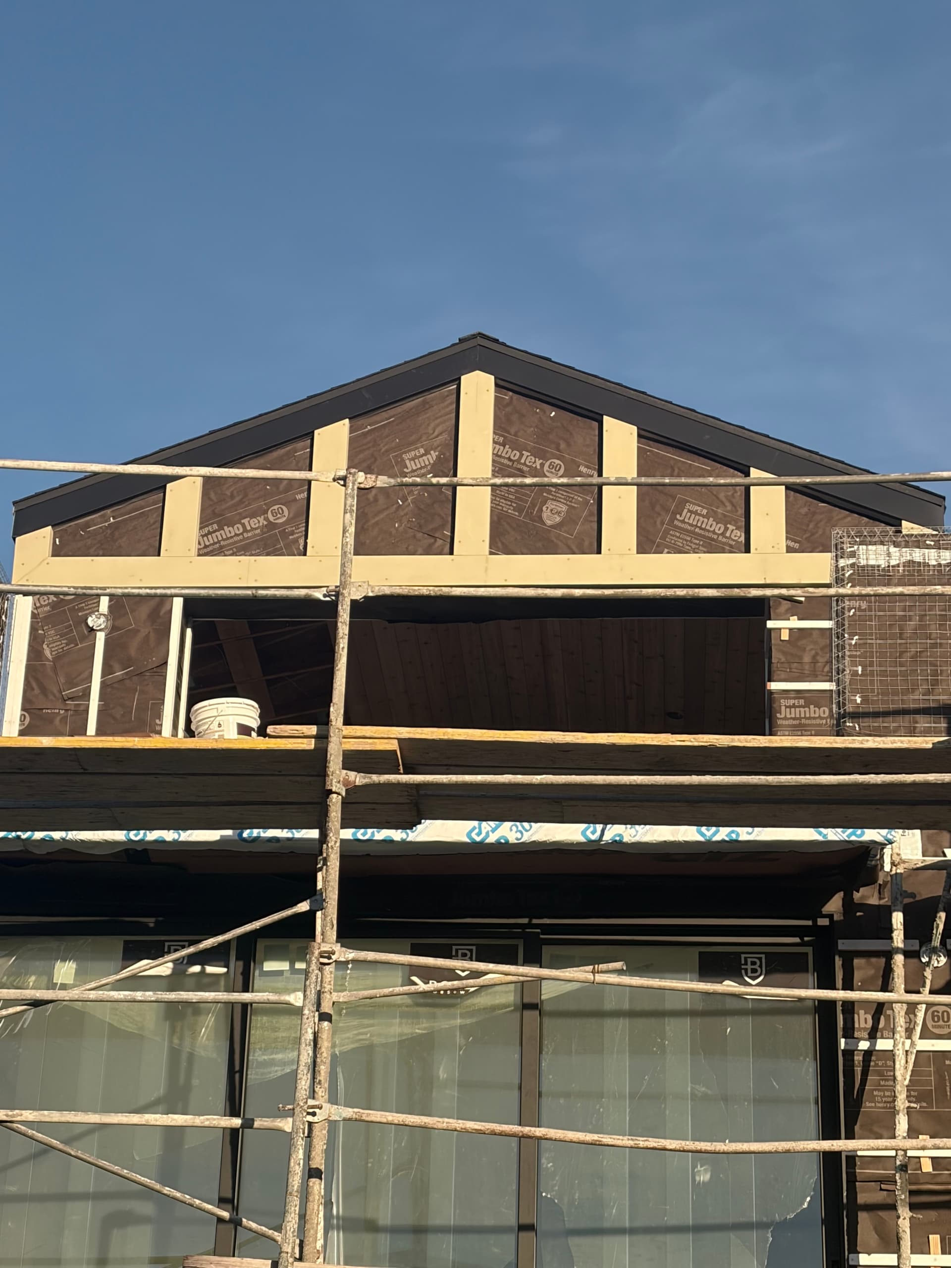 Full exterior view of aluminum fascia wrap installation on new construction with scaffolding