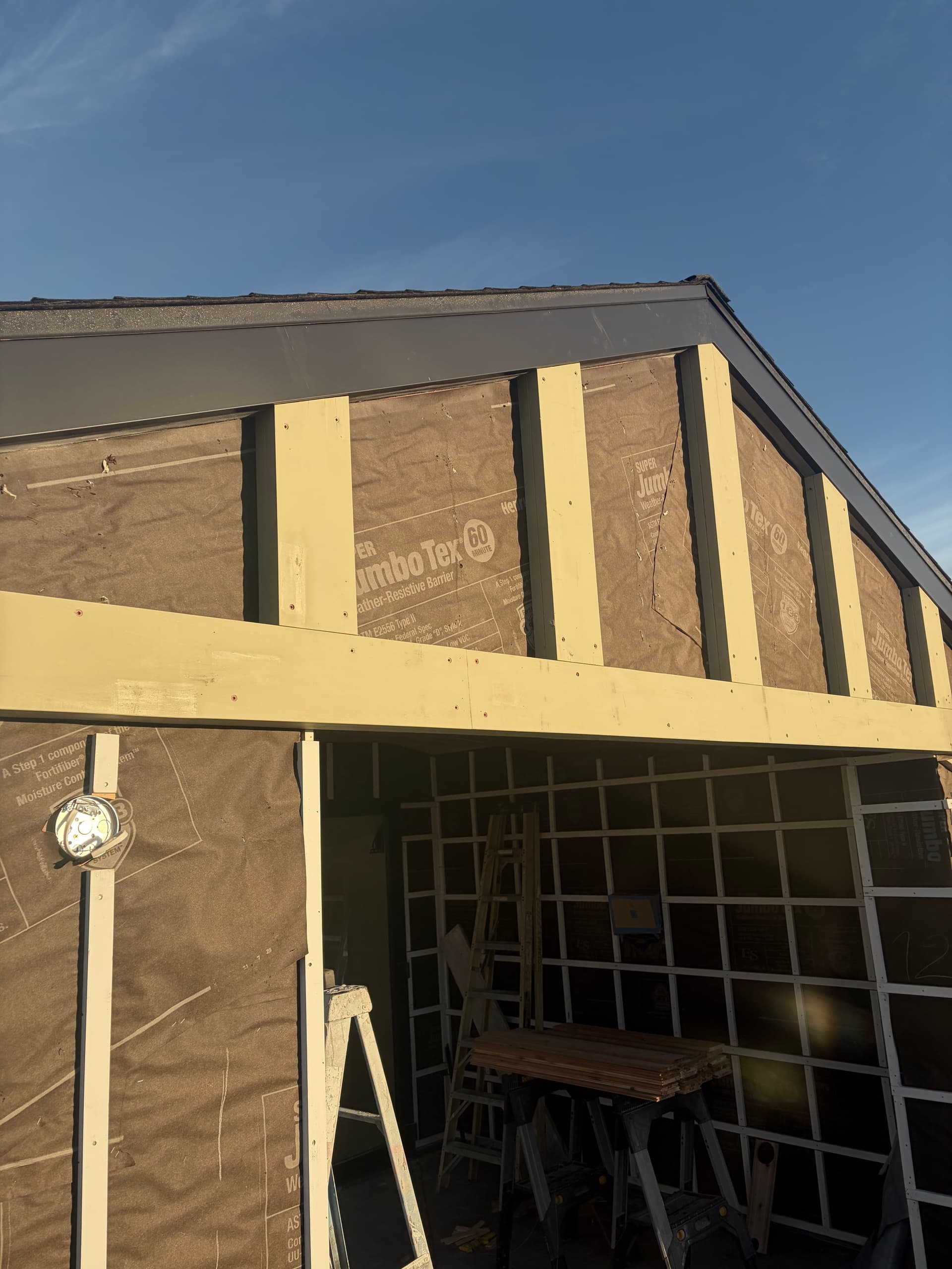 Aluminum clad fascia wrap in progress on new construction roofline with exposed rafter tails