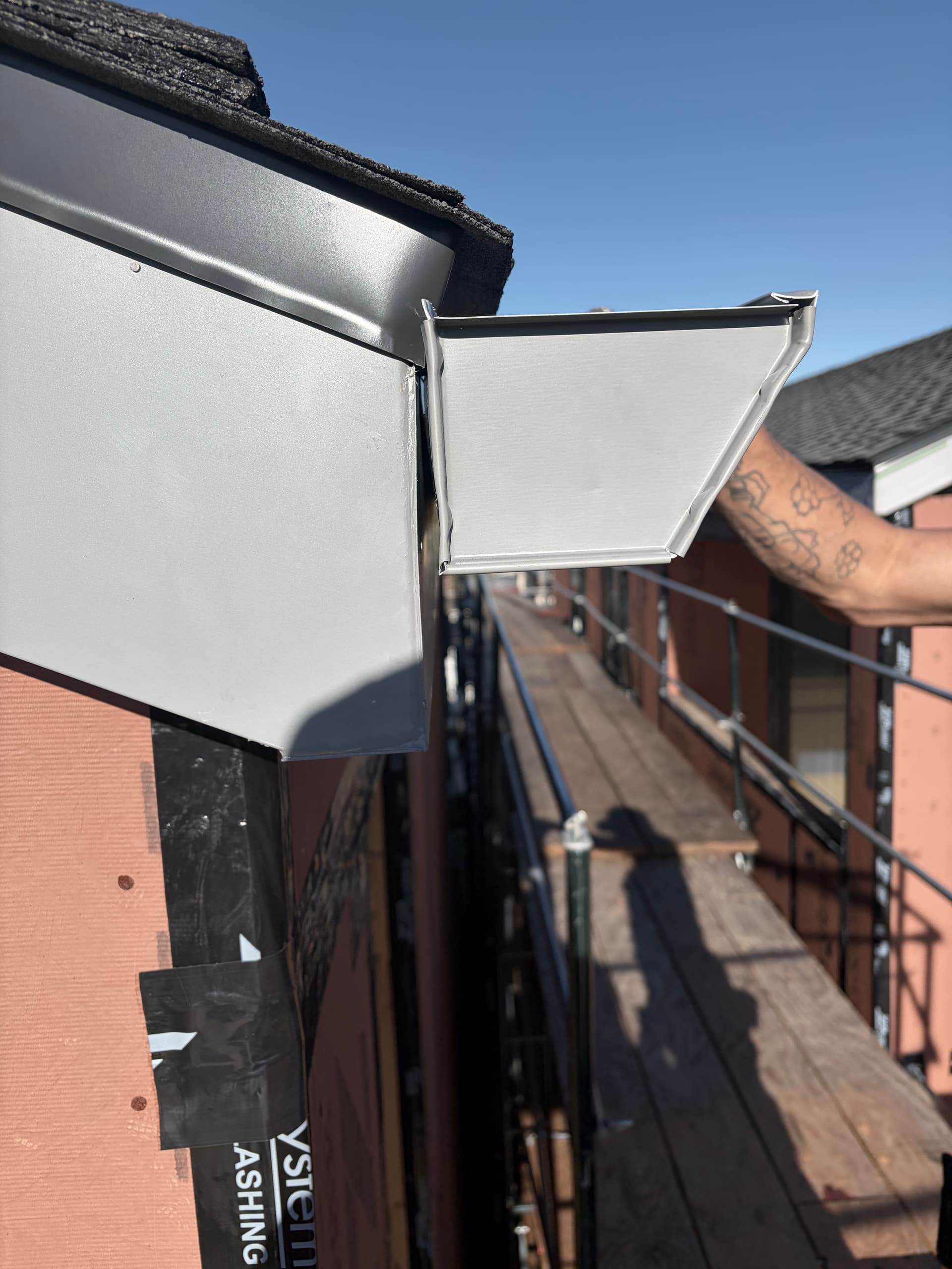 White aluminum fascia wrap corner piece being installed by hand on new construction