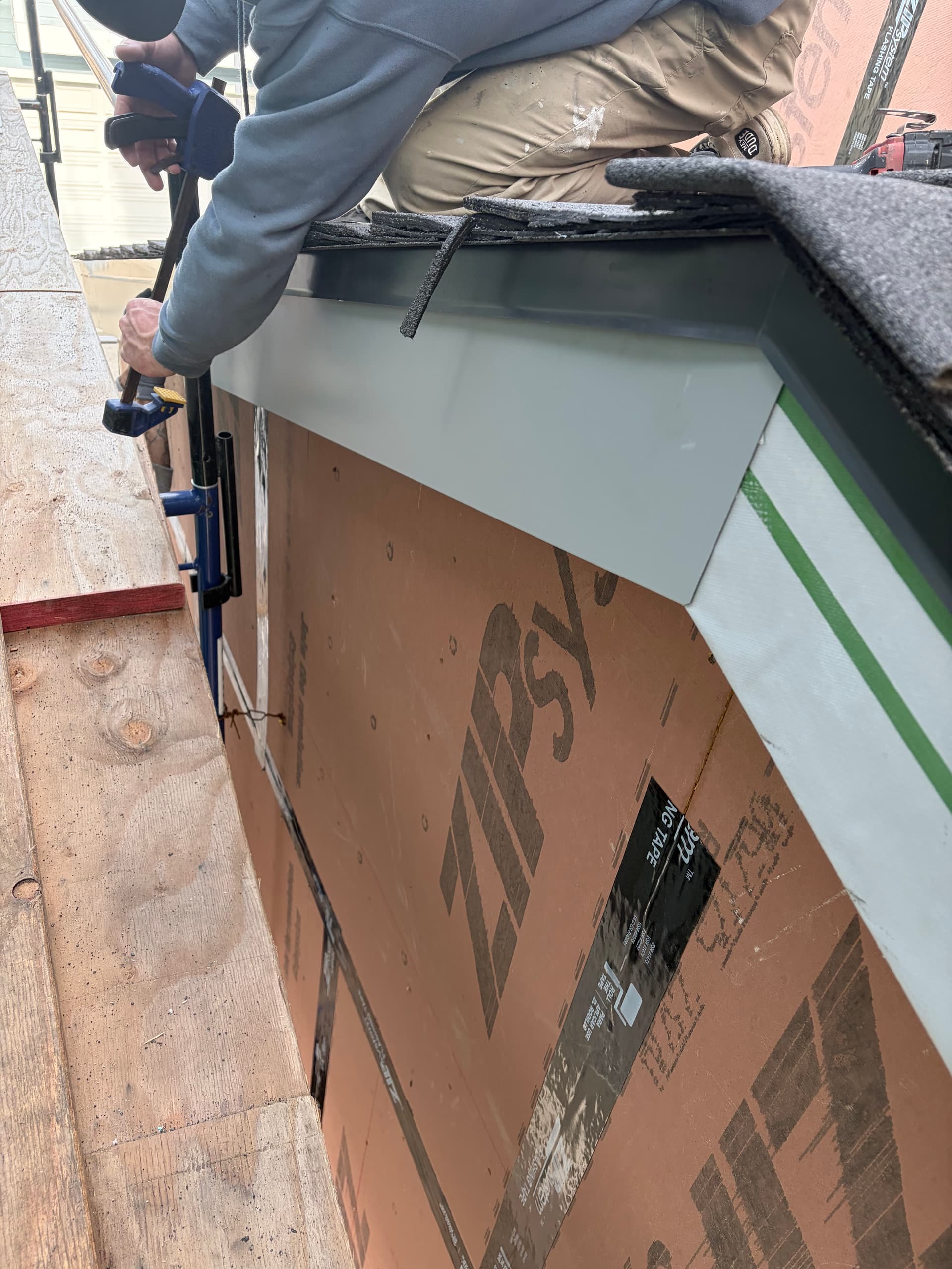 Installer securing white aluminum fascia wrap with drill on new construction