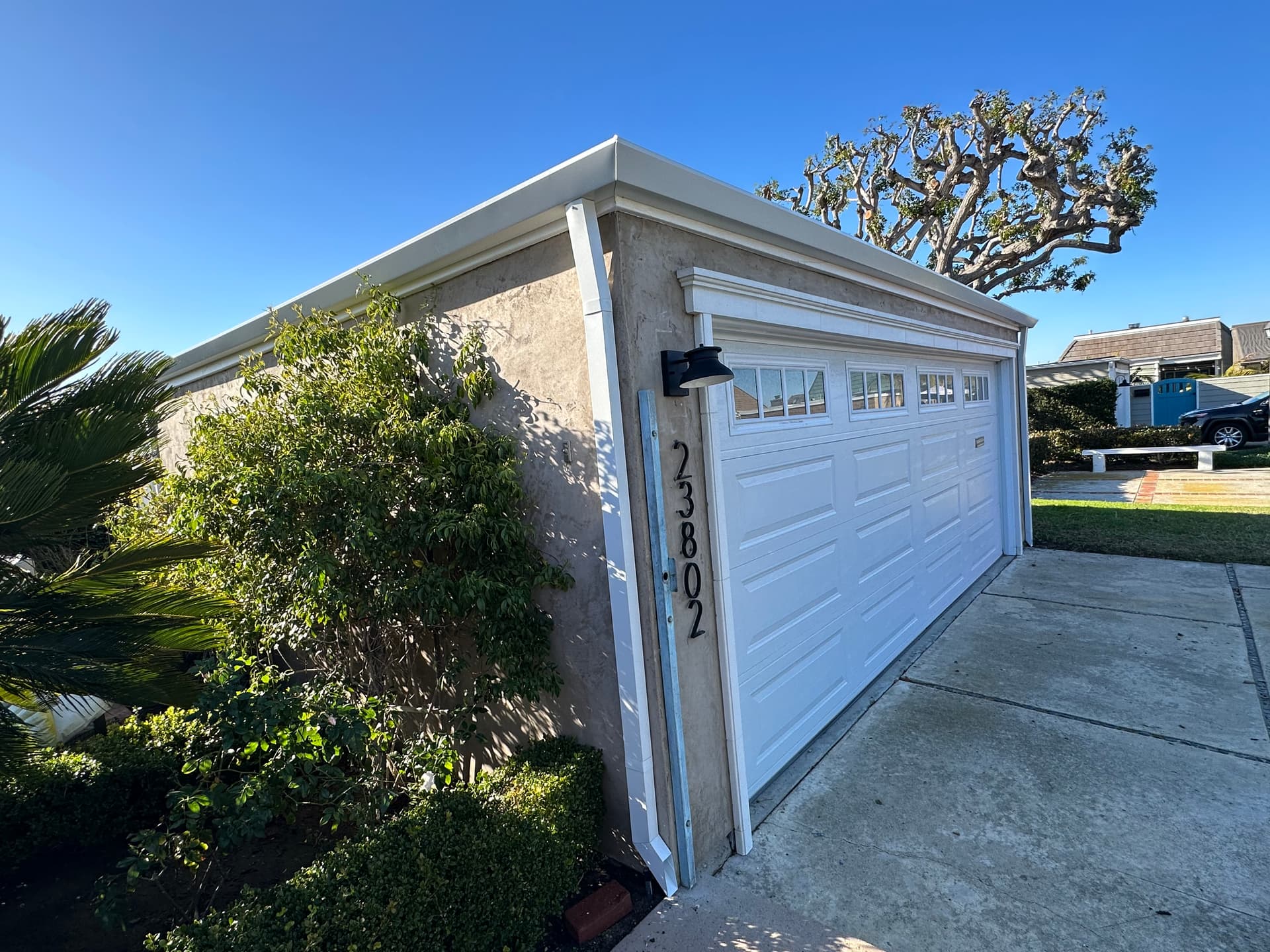 White seamless gutter installation on a garage roofline in a coastal neighborhood