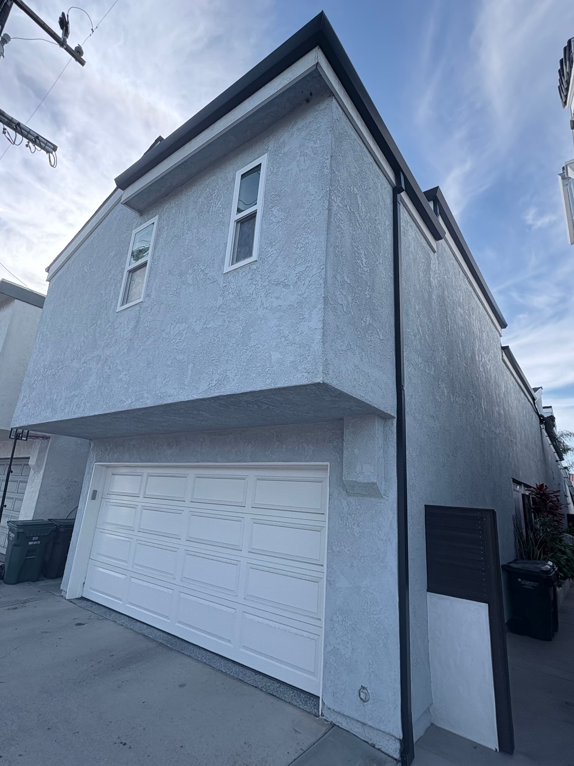 Dark seamless gutter on a two-story stucco home front elevation with garage