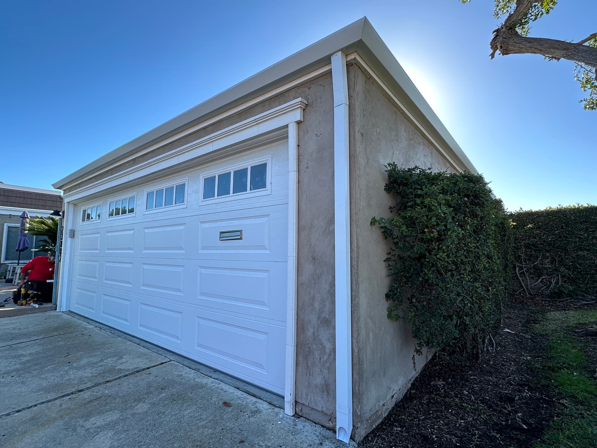 White seamless gutter along a residential garage roofline with sun backlight