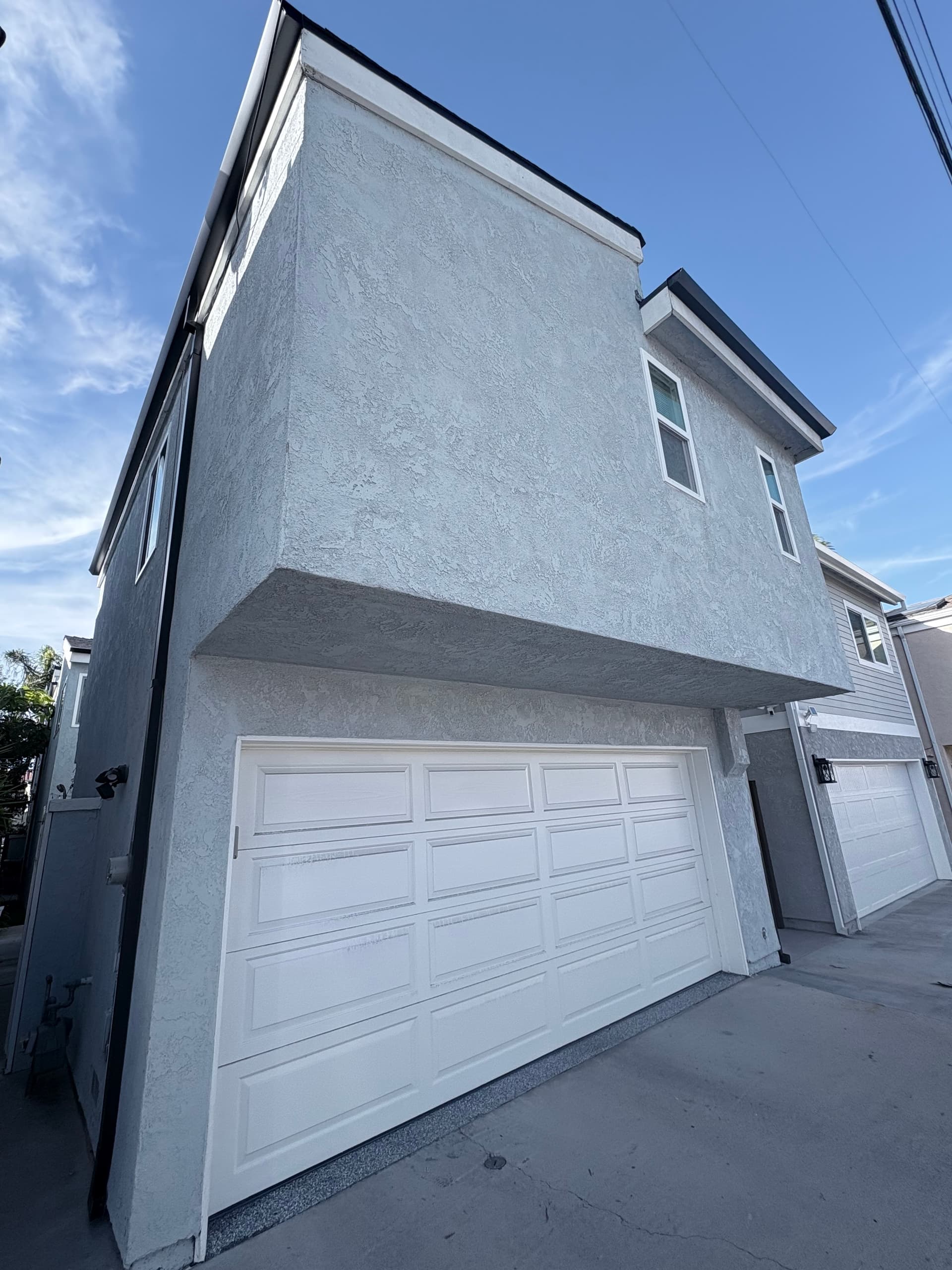 White seamless gutter on a two-story stucco home with garage